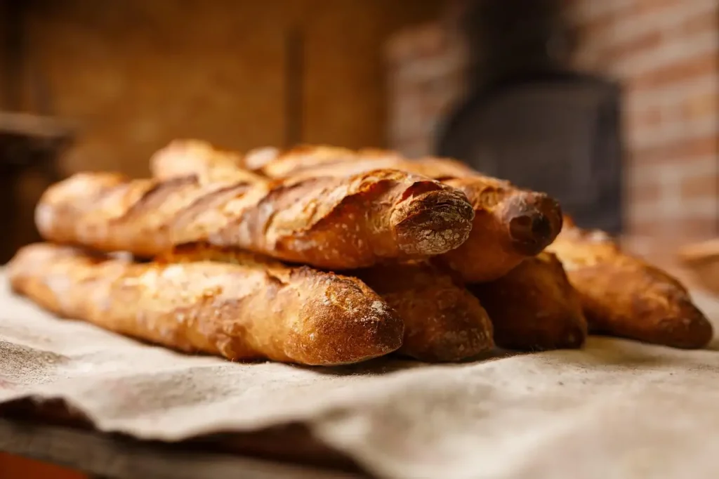 Baguettes dorées empilées sur une toile de lin devant le four d'une boulangerie