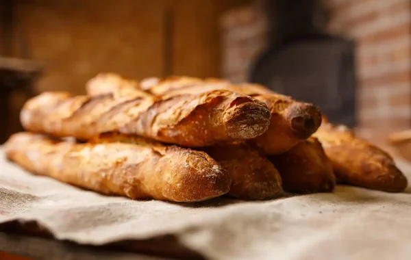Baguettes dorées empilées sur une toile de lin devant le four d'une boulangerie