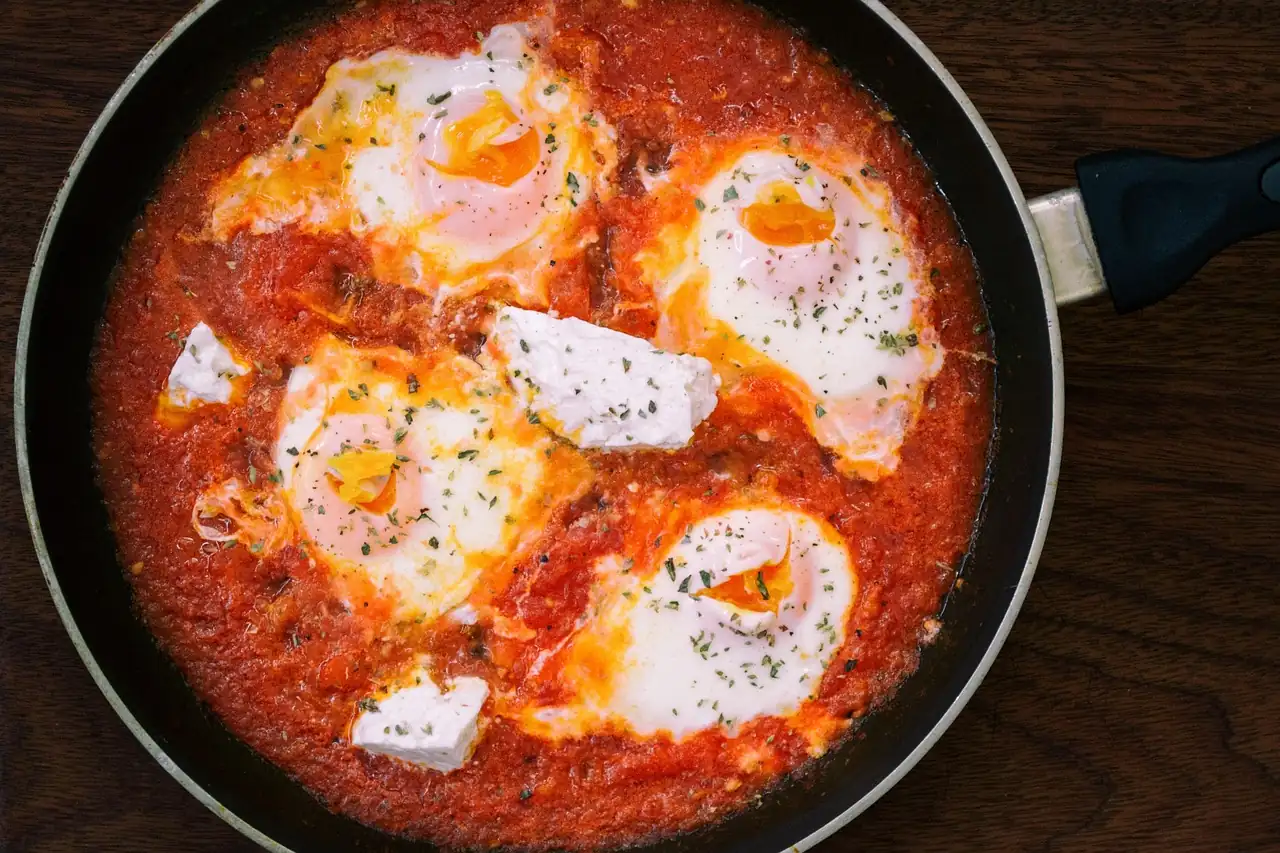 Œufs pochés dans une sauce tomate avec du fromage frais, dans une poêle vue de dessus