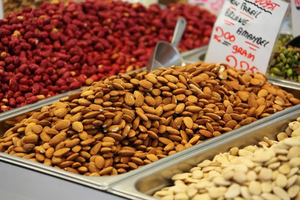 Bacs d'amandes et de fruits secs sur un étal de marché, avec une étiquette de prix manuscrite
