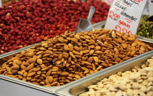 Bacs d'amandes et de fruits secs sur un étal de marché, avec une étiquette de prix manuscrite
