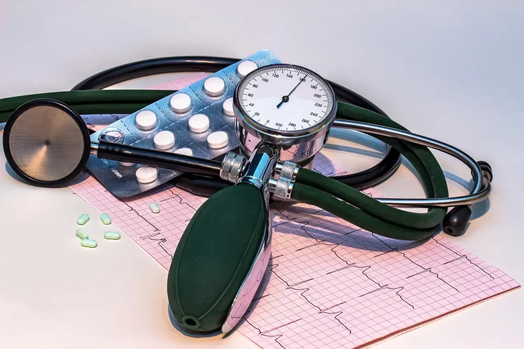 Tensiomètre manuel à cadran gradué, stéthoscope et tracé d'électrocardiogramme posés côte à côte