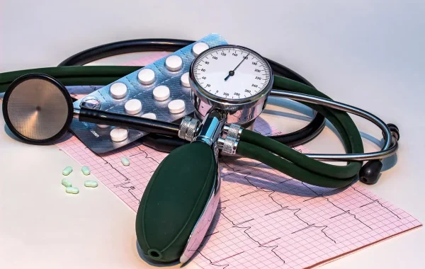 Tensiomètre manuel à cadran gradué, stéthoscope et tracé d'électrocardiogramme posés côte à côte