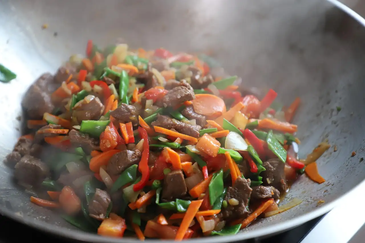 Wok fumant rempli de légumes colorés et de morceaux de viande sautés