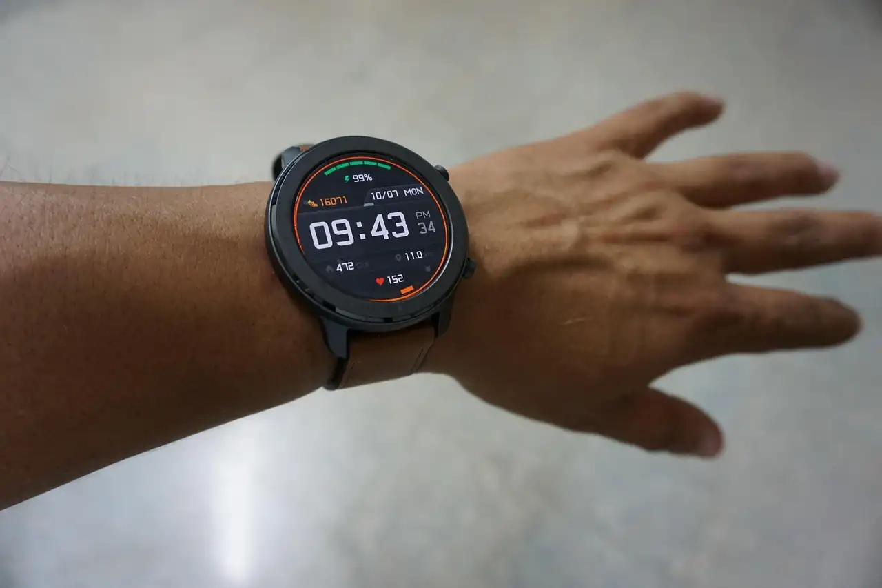Poignet d'un homme portant une montre connectée dont l'écran affiche l'heure et une fréquence cardiaque