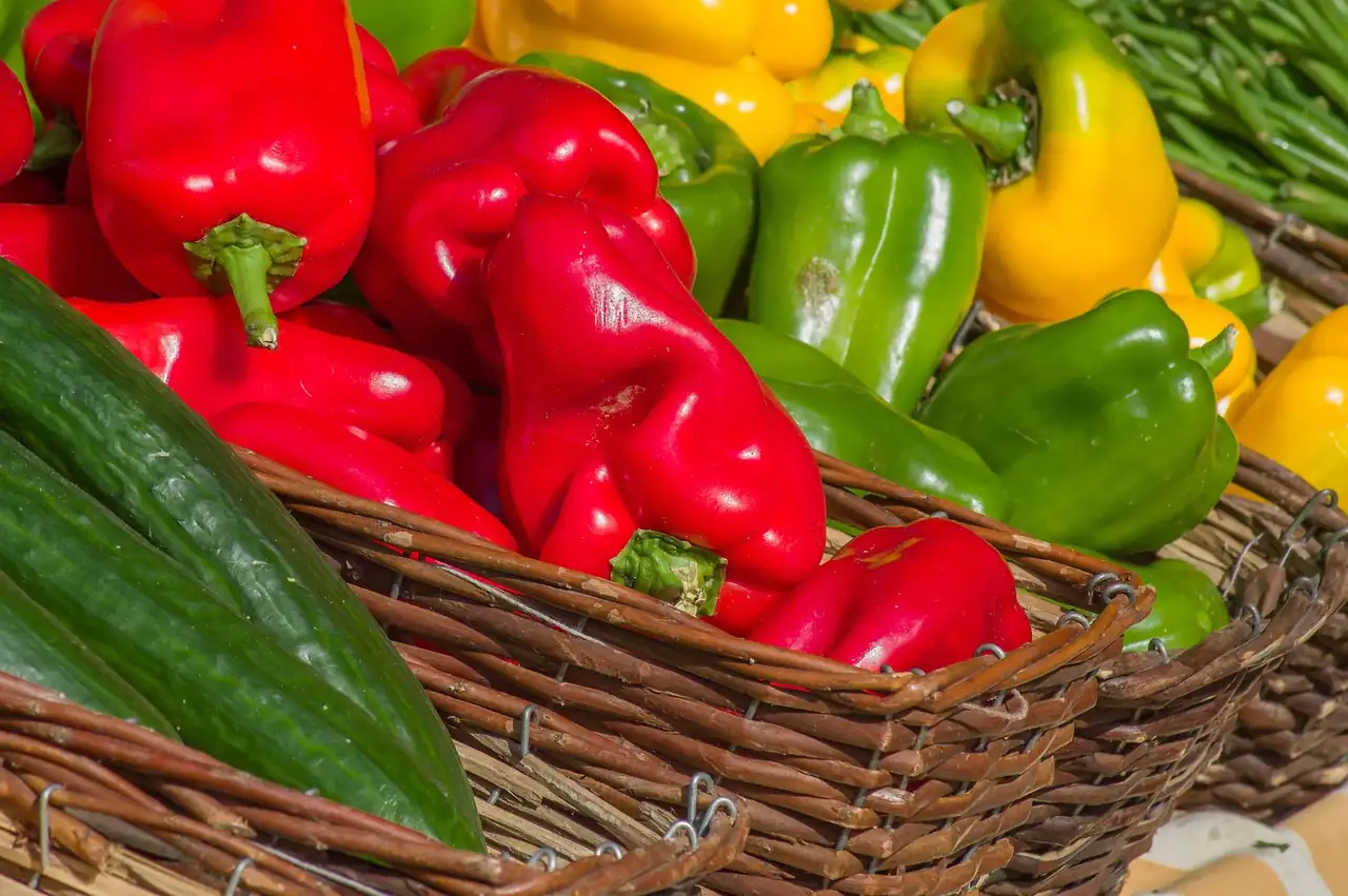 Poivrons rouges, verts et jaunes dans des paniers en osier sur un étal de marché
