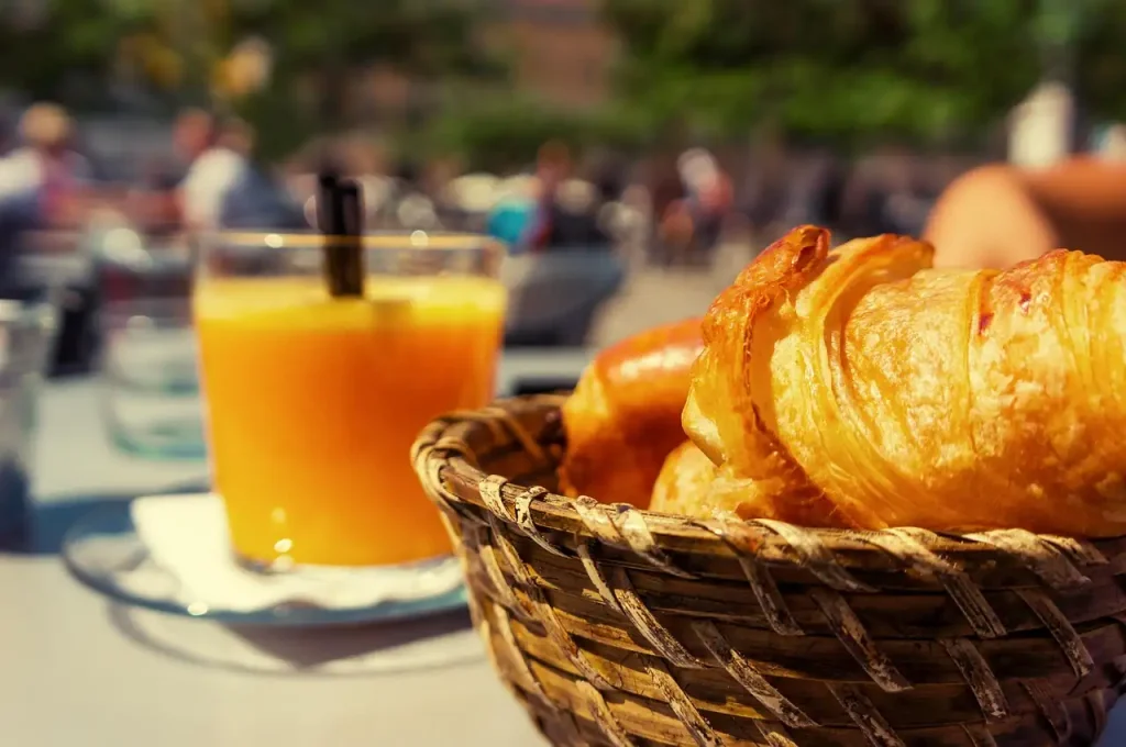 Corbeille de croissants et verre de jus d'orange sur une table en terrasse au soleil