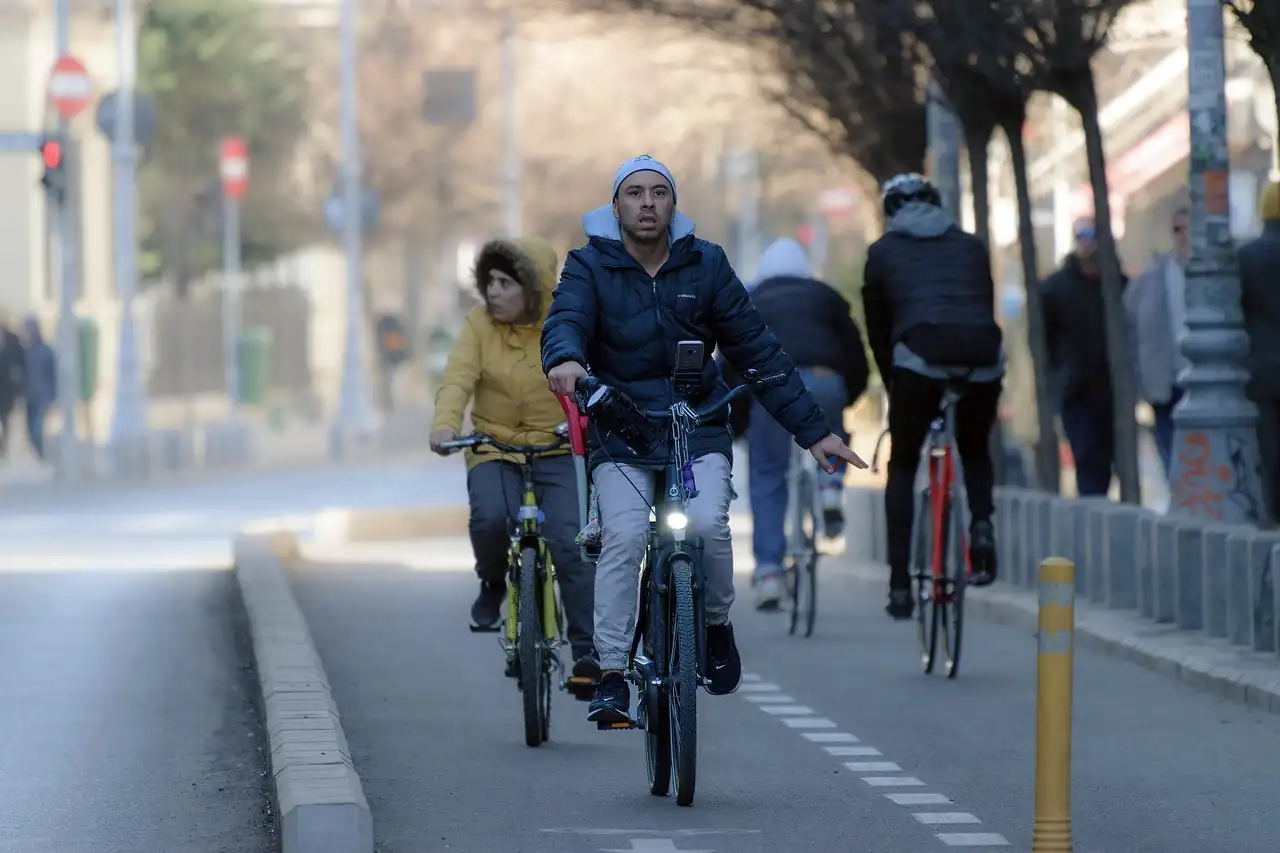 Groupe de cyclistes en doudoune sur une piste cyclable en ville, un matin d'hiver