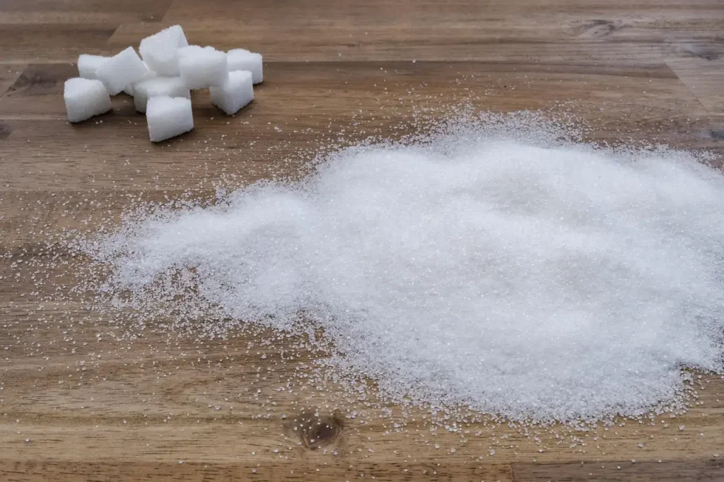 Morceaux de sucre et tas de sucre en poudre étalé sur une table en bois