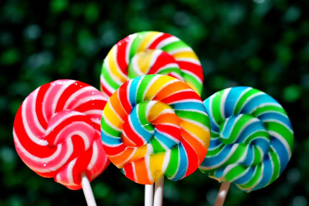 Trois grosses sucettes en spirale aux couleurs vives sur un fond de feuillage vert