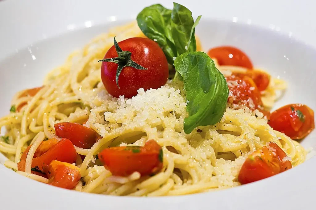 Assiette de spaghetti aux tomates cerises, parmesan râpé et feuilles de basilic frais