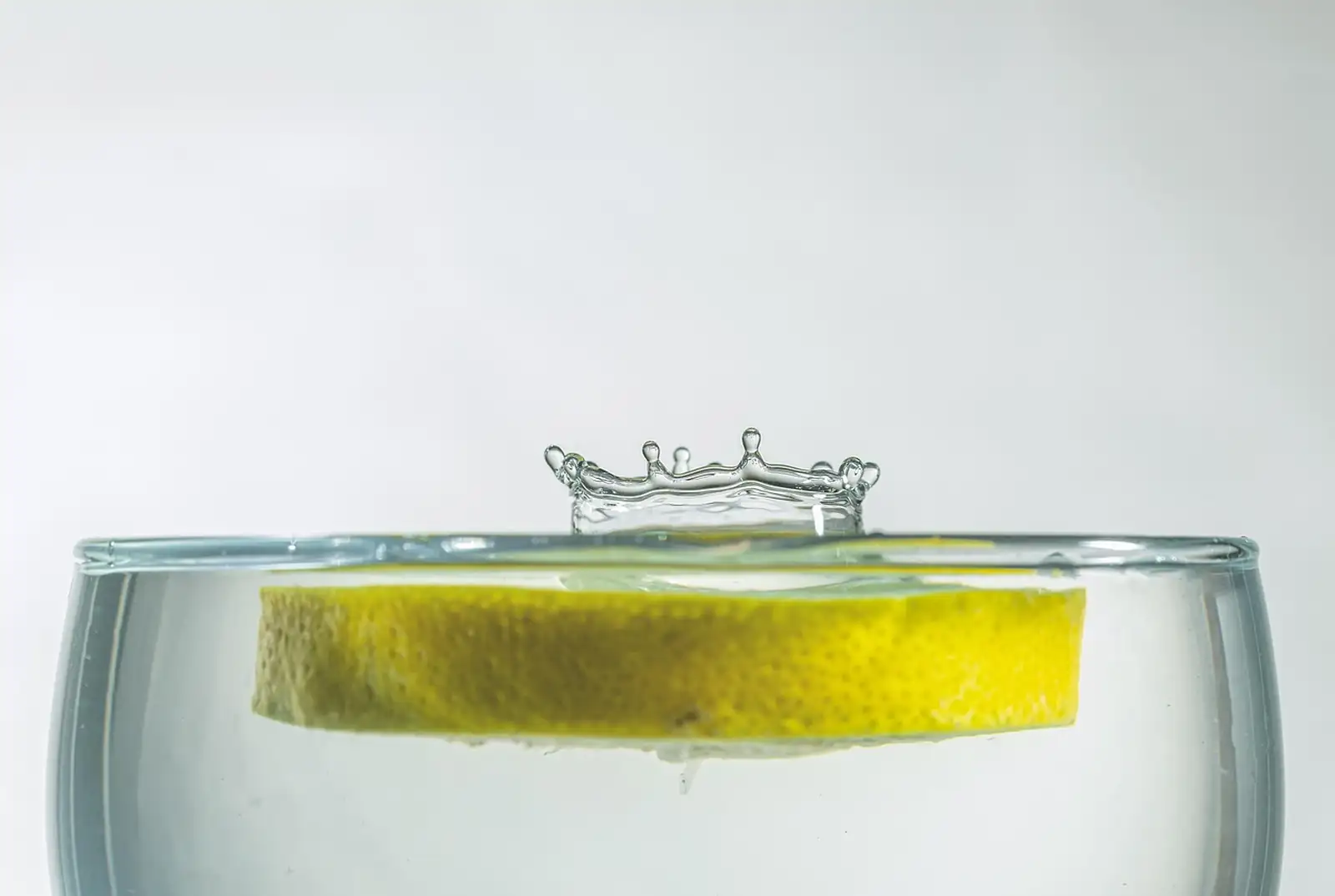 Rondelle de citron qui flotte à la surface d’un verre d’eau, avec une petite éclaboussure