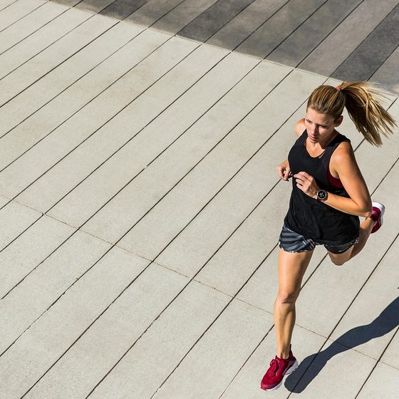 Femme courant en extérieur sur une terrasse en bois, exercice cardio-training