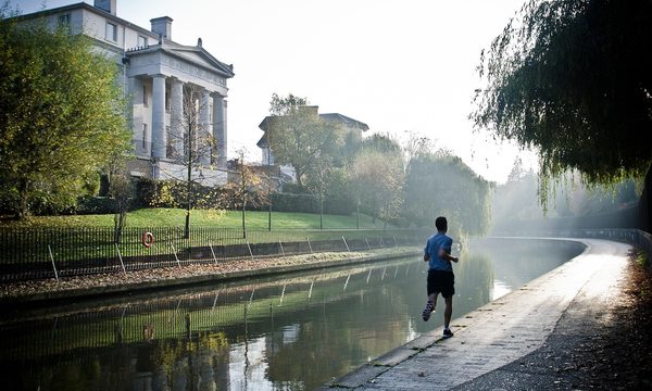Homme pratiquant la course à pied le long d'un canal, ambiance matinale brumeuse